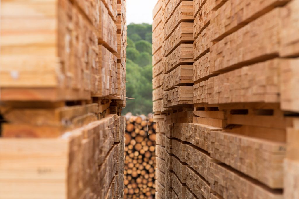 Pasillo entre pilas de tablones de madera almacenados